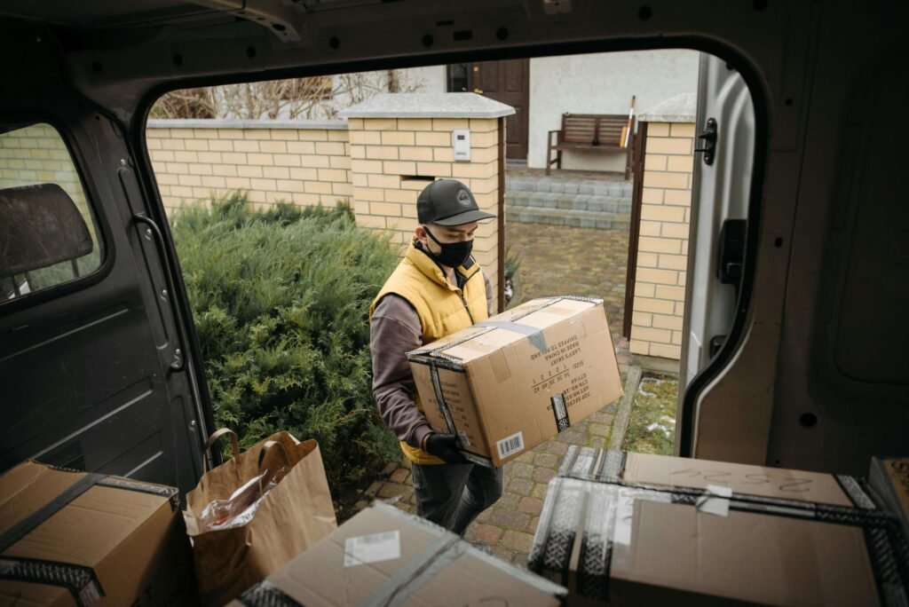 courier holding a parcel next to the van